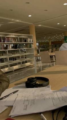 a table with papers and headphones on it in a room full of bookshelves