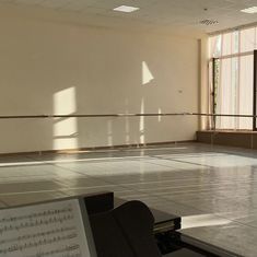 an empty room with sheet music on the floor and large windows in the back ground