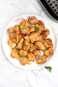 chicken bites on a plate with parsley garnish in the bowl next to it