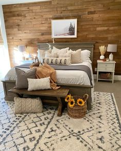 a bed with pillows and blankets on top of it in front of a wooden wall