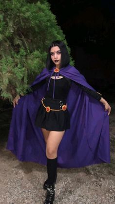 a woman dressed in a costume and cape posing for the camera with her hands on her hips