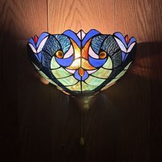 a stained glass wall light hanging on a wooden wall