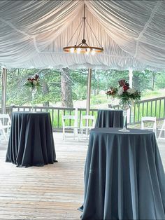 tables covered with blue tablecloths under a white tent