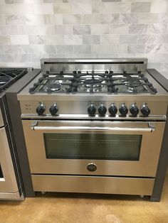 a stainless steel stove top oven sitting next to an oven with two burners on each side