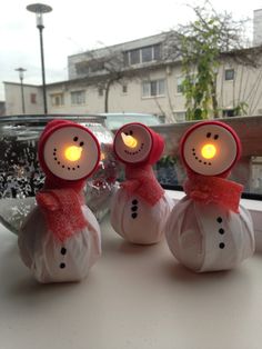 three snowmen with lights on their heads are sitting in front of a window sill