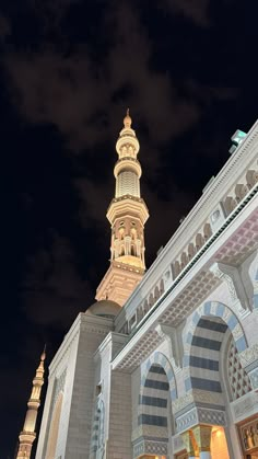 an ornate building lit up at night with clouds in the background