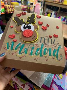 someone holding up a cardboard box decorated with hearts and reindeer's face on it