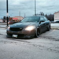 a gray car parked in a parking lot next to a building and traffic lights on a cloudy day