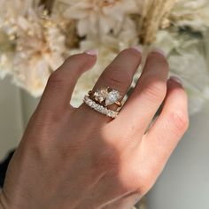 a woman's hand with two diamond rings on her left and the other hand holding a bouquet of flowers