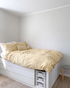 a bed sitting on top of a wooden floor next to a white wall and window