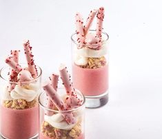 three desserts in small glass cups with candy sticks sticking out of them