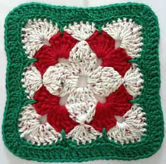 a crocheted square with red, white and green flowers in the center on a white surface