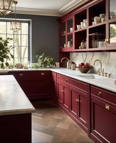 a kitchen with red cabinets and marble counter tops