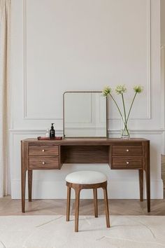 a wooden desk with two drawers and a mirror on top of it next to a stool