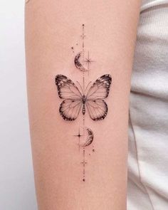 a woman's arm with a butterfly and half moon tattoo on the left side