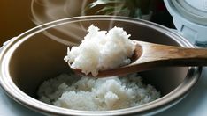 a wooden spoon with rice in it on top of a pot filled with water and steam