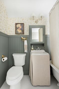 a white toilet sitting next to a bath tub under a bathroom mirror above a sink