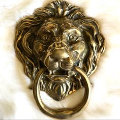 a brass lion head door knocker on a white fur surface with a ring in the middle