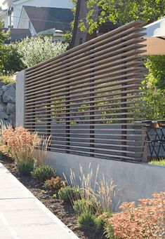 an outdoor area with plants, rocks and wooden slatted fence on the side