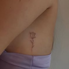 a woman's stomach with a single flower tattoo on her left side ribcage