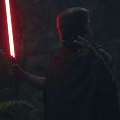 a person holding a light saber in the dark with red lights on their face and hands