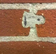 a close up of a brick wall with a hole in the middle and a dog's head on it