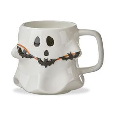 a white coffee mug with black and orange bats painted on the outside of it's face