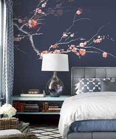 a bedroom decorated in blue and white with flowers on the wall, bed, nightstands and lamp