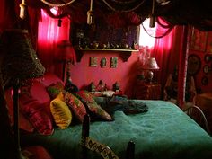 a bedroom with red curtains and green bedspread on the bed is lit by two lamps