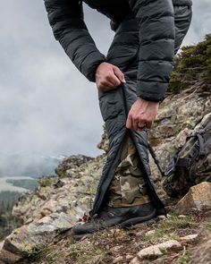 a man is tying his jacket on the side of a mountain