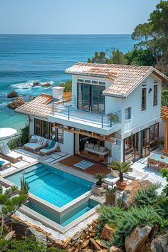 an aerial view of a house with a swimming pool in the foreground and ocean in the background