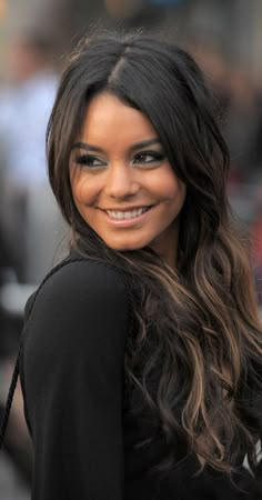 a woman with long dark hair smiling at the camera