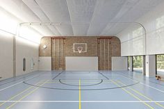 an indoor basketball court with white walls and yellow lines painted on the floor is shown