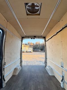 the inside of an empty van with wood flooring and large windows on both sides