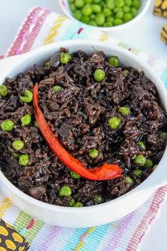 a white bowl filled with black rice and red pepper on top of a colorful table cloth