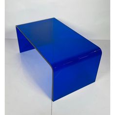 a blue glass table sitting on top of a white floor in front of a wall