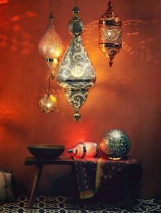 an assortment of decorative lights hanging from the ceiling in front of a table with a bowl on it