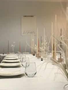 a long table is set with white plates and glasses