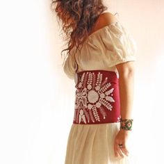 a woman in a white dress is wearing a red and white belt with flowers on it