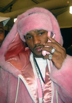 a man in a pink fur coat talking on a cell phone while wearing a ring