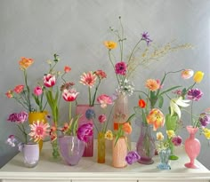 a table topped with lots of vases filled with different types of flowers on top of it