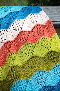 a colorful crocheted blanket sitting on top of a wooden bench