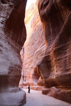 a man standing in the middle of a narrow canyon