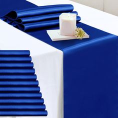 a blue and white table cloth with a candle on it next to some napkins