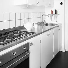 a black and white photo of a kitchen with an oven, stove top and cabinets