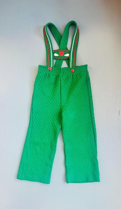 Vintage 1970s Carter's overalls.  Dutch/Swiss in style, perfect colors for the Christmas holiday or a cute every day look.  Unisex, size 4T. Features dark kelly green with a diamond embossed pattern on the fabric.  The waist has two red buttons and the straps have red/white bric-a-brac trim with an affixed red heart and two white petals in the center.   The back straps criss-cross.  In good vintage condition with no stains or holes. Thank you for reviewing our policies below and for your visit to Maple Clover Vintage! We handpick an eclectic mix for vintage treasures for the home, child and wardrobe. Browse the rest of our shop for more vintage treasures. Shipping:  USPS Standard Post (insurance tracking included) We are happy to ship internationally! *Due to the variability in shipping co Christmas Overalls, Retro Overalls, Eclectic Outfits, Green Boys, Xmas Outfit, Dutch Style, Vintage Kids Clothes, Outfit Retro, Kids Overalls