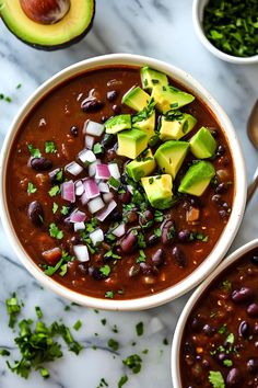 two bowls filled with black beans and avocado on top of a marble table