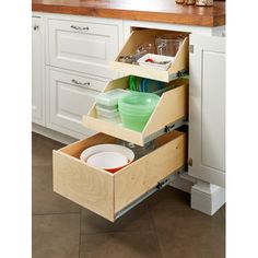 an open drawer in the middle of a kitchen with plates and bowls on it's bottom shelf