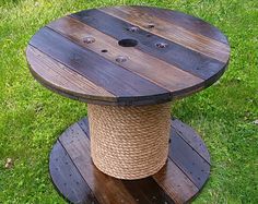 a spool of rope is attached to a round wooden table on the grass lawn