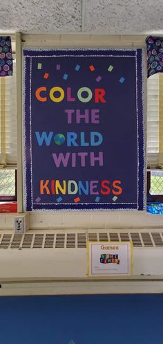 a bulletin board with the words color the world with kindness on it in front of windows